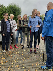 Grupa osób w terenie, instruktor demonstruje kijki do nordic walking