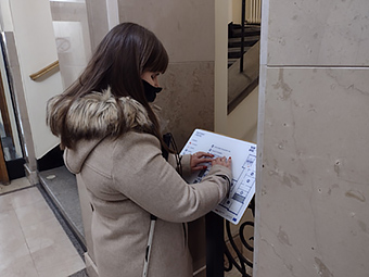 kobieta czytająca tablicę tyflograficzną przed rektoratem