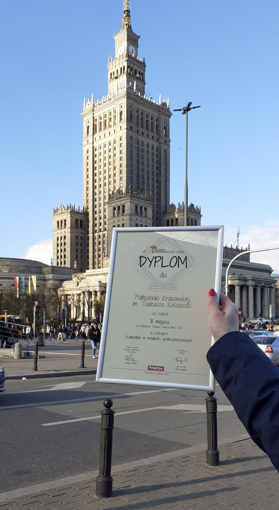 Dyplom dla PK sfotografowany na tle Pałacu Kultury i Nauki w Warszawie