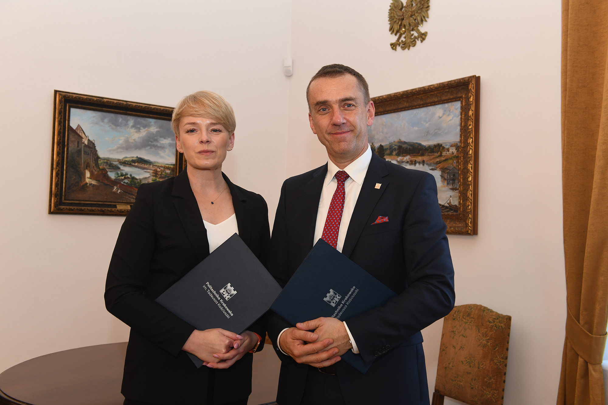 Katarzyna Rybus i prof. Andrzej Szarata pozują do zdjęcia, w ręce trzymają teczki z umową