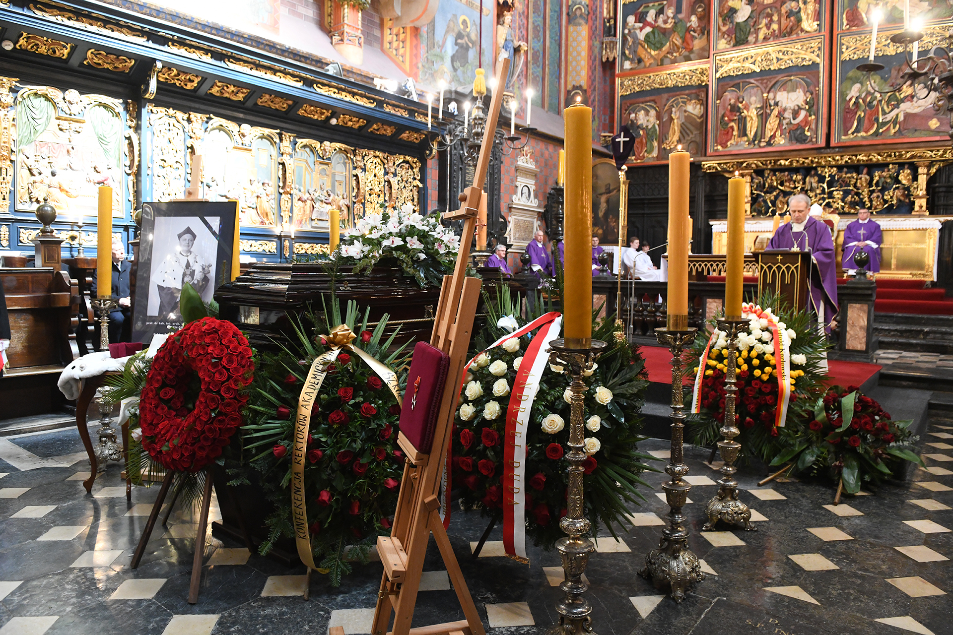 trumna ś.p. rektora Andrzeja Białkiewicza przed ołtarzem mariackim, obok portret i wieńce kwiatów, pry ołtarzu księża