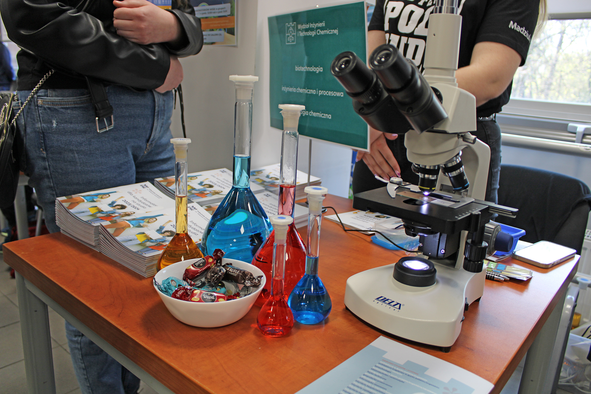 Aparatura laboratoryjna: mikroskop i kolby z kolorowymi płynami