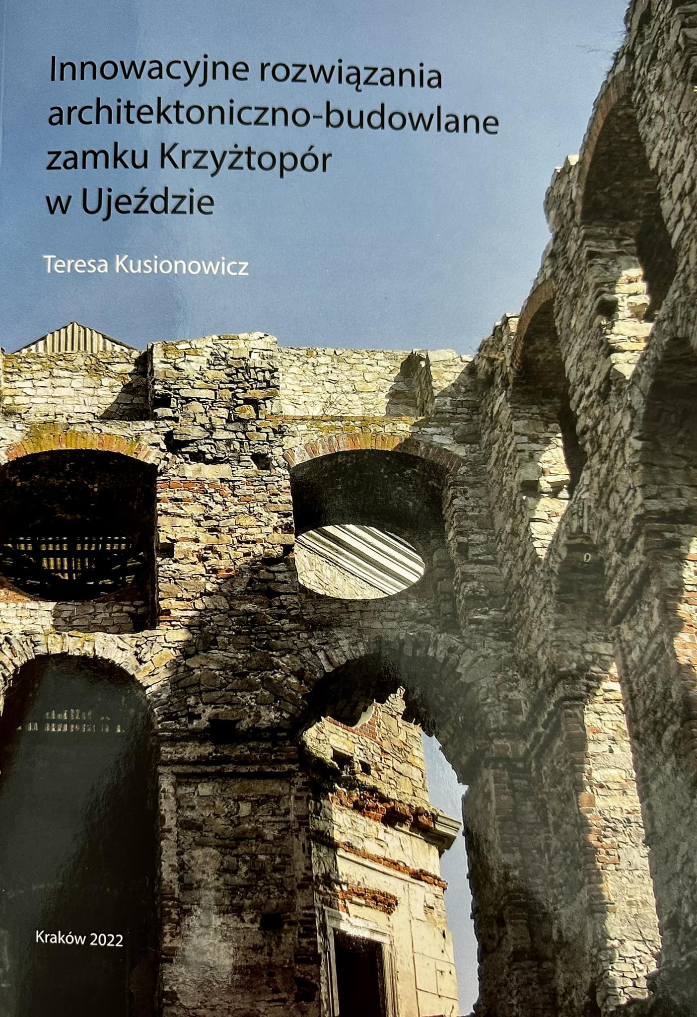 Okładka książki to zdjęcie fragmentu ściany zamku Krzyżtopór. Na górze znajduje się tytuł książki i nazwisko autora, a na dole napis Kraków 2022. 