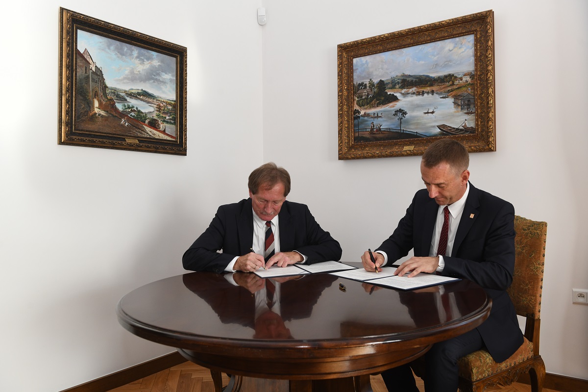 Przewodniczący Rady MOIIB Mirosław Boryczko (od lewej) i rektor PK prof. Andrzej Szarata podpisują umowę o współpracy, siedzą przy okrągłym stole