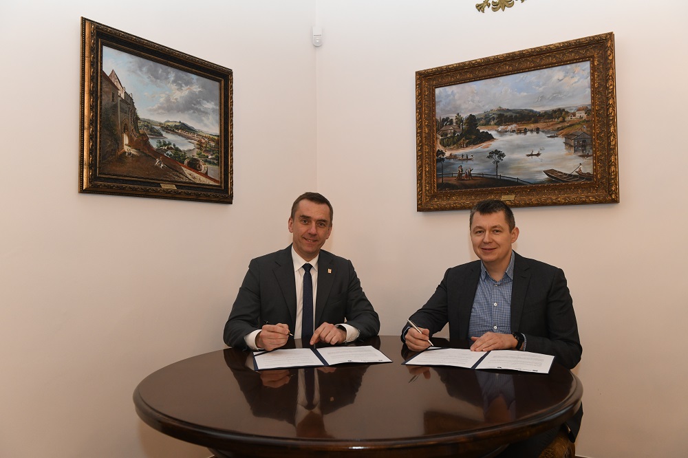 Przy stole siedzą rektor PK prof. Andrzej Szarata i dyrektor MCN „Cogiteon” Piotr Szymański , trzymają w rękach długopisy. Na stole leżą umowy